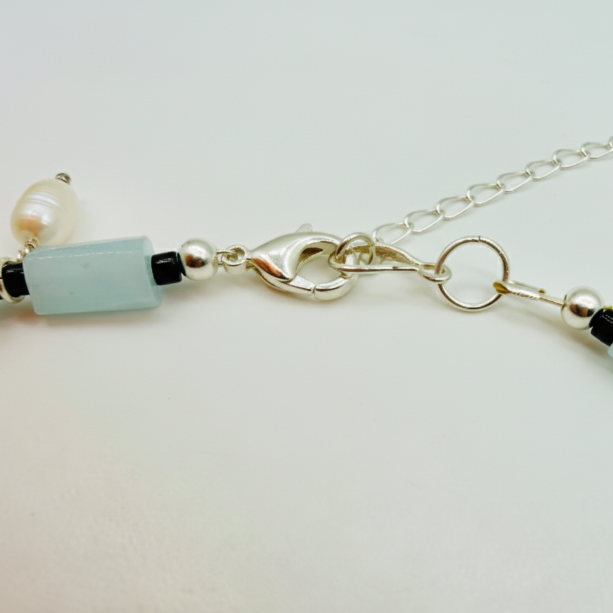 Necklace with light blue beads and silver chain on a white background