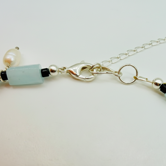 Necklace with light blue beads and silver chain on a white background