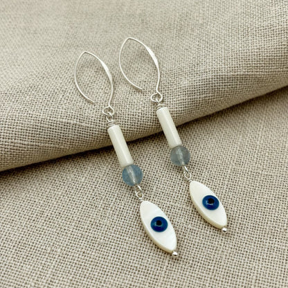 A pair of extra-long 76mm dangle earrings featuring a mother of pearl evil eye and an aquamarine bead.