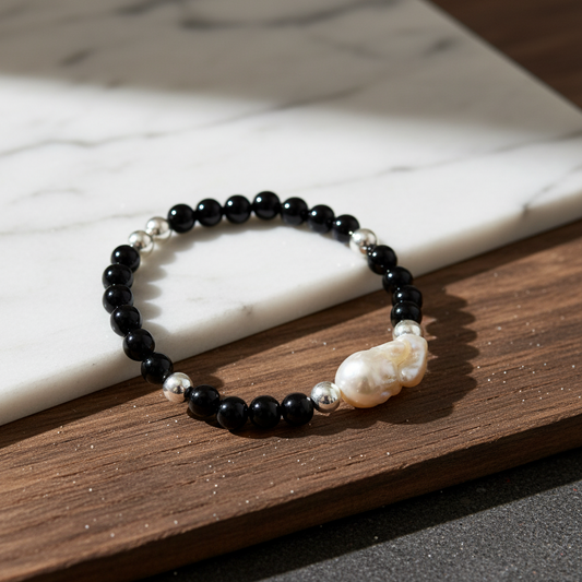 A 15cm stretch bracelet featuring black obsidian beads, silver-plated accents, and a large baroque pearl.