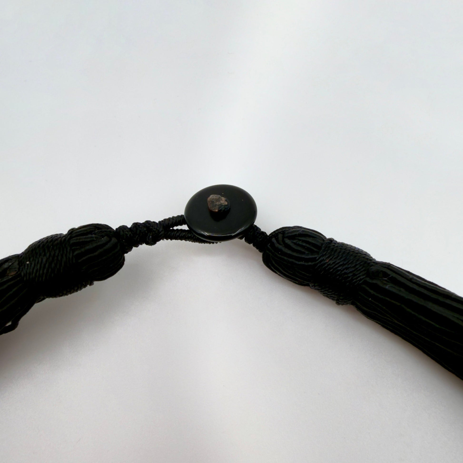 Black braided cord with a button on a white background