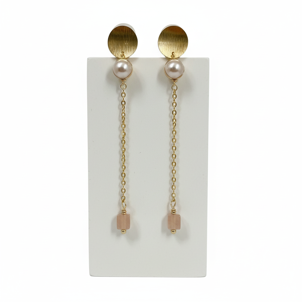 Pair of gold earrings with pearl-like beads on a white card