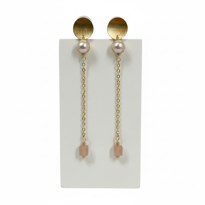 Pair of gold earrings with pearl-like beads on a white card