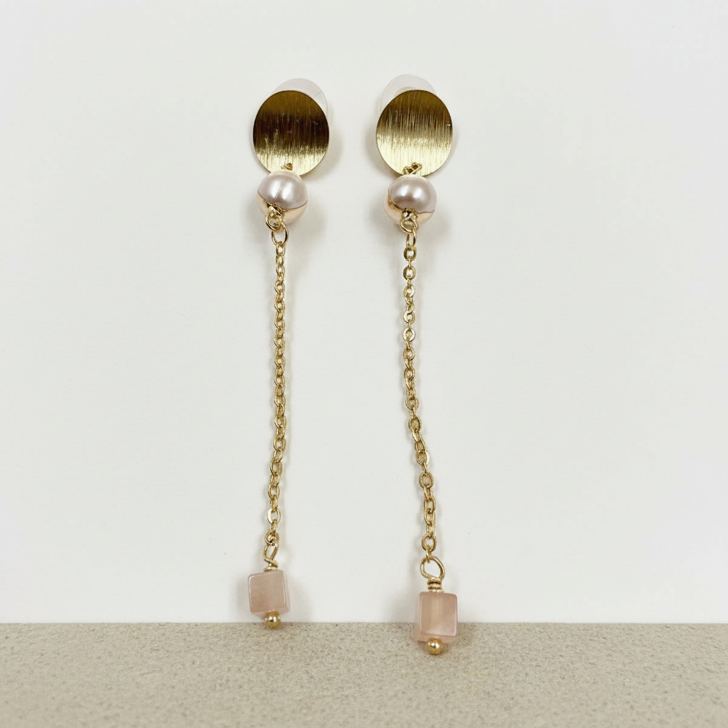Pair of gold earrings with pearl and gemstone accents on a light background