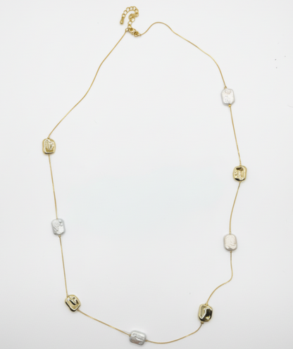 Gold necklace with various beads on a white background