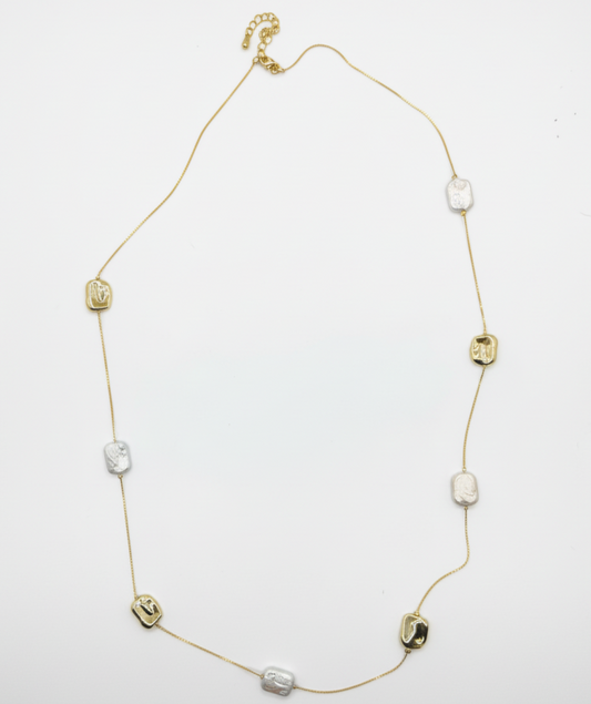 Gold necklace with various beads on a white background