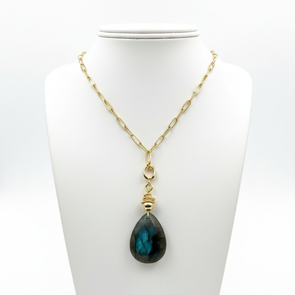 Necklace with a blue teardrop pendant on a white stand