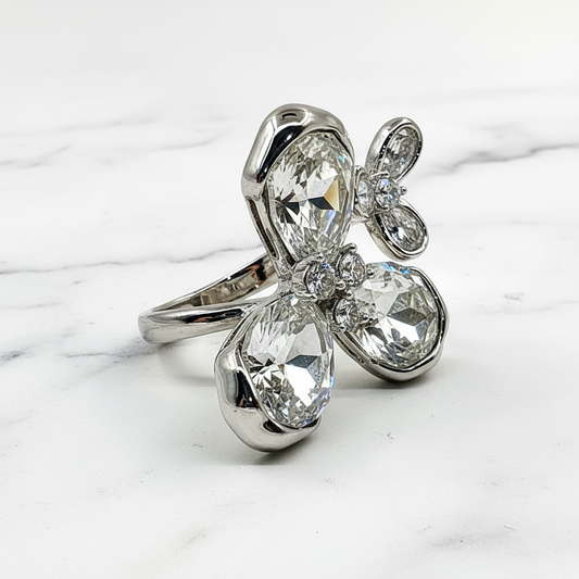 Silver ring with large clear gemstones on a marble surface