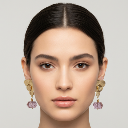 Woman wearing gold earrings with pink gemstones against a neutral background